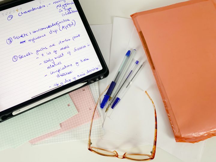 Study desk with an iPad pro and Apple Pencil, some blank papers, pens, a folder and some computer glasses