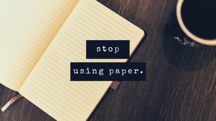 Image shows a paper notebook and a cup of black coffee on a dark-brown table.